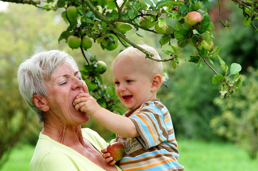 ältere Frau mit Kind unter einem Apfelbaum