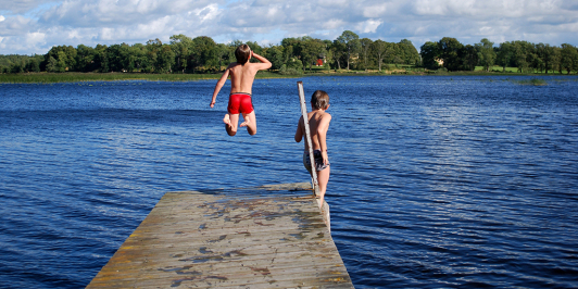 Auf dem Bild sind zwei Jungen zusehen, welche in einen See springen.